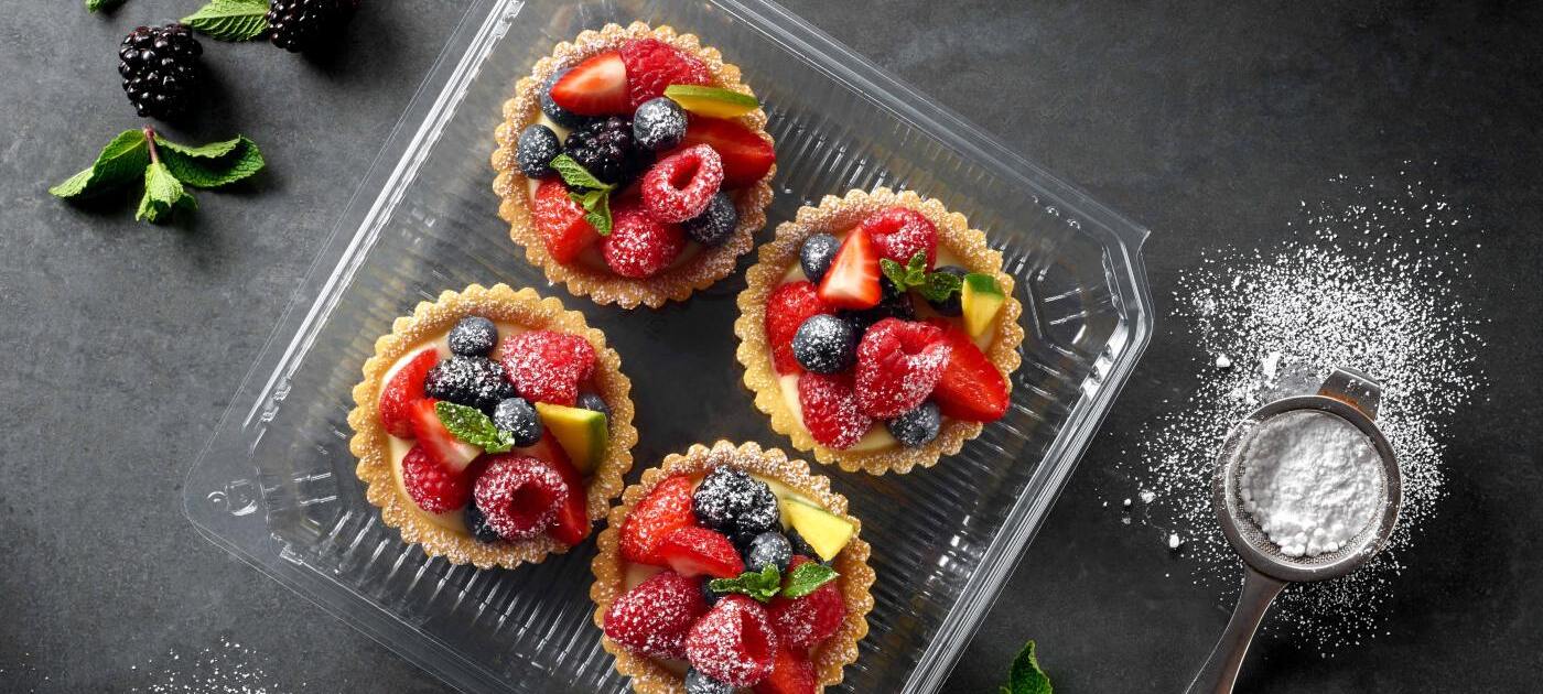  Picture showing four cupcakes in a transparent PET food packaging tray. 