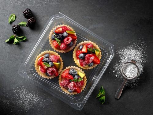 Picture showing four transparent food packaging trays for bakery products with cakes inside