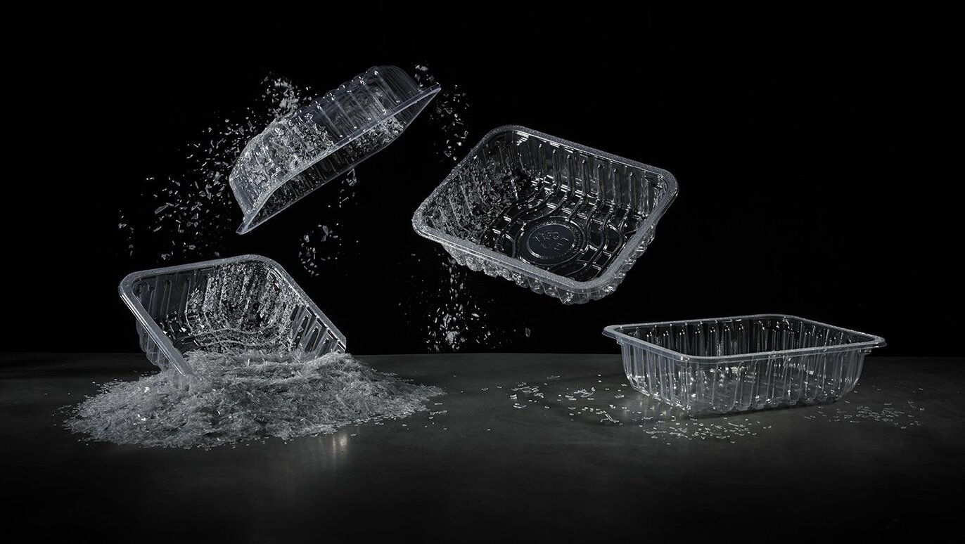 This images shows various empty transparent food packaging trays on a black background