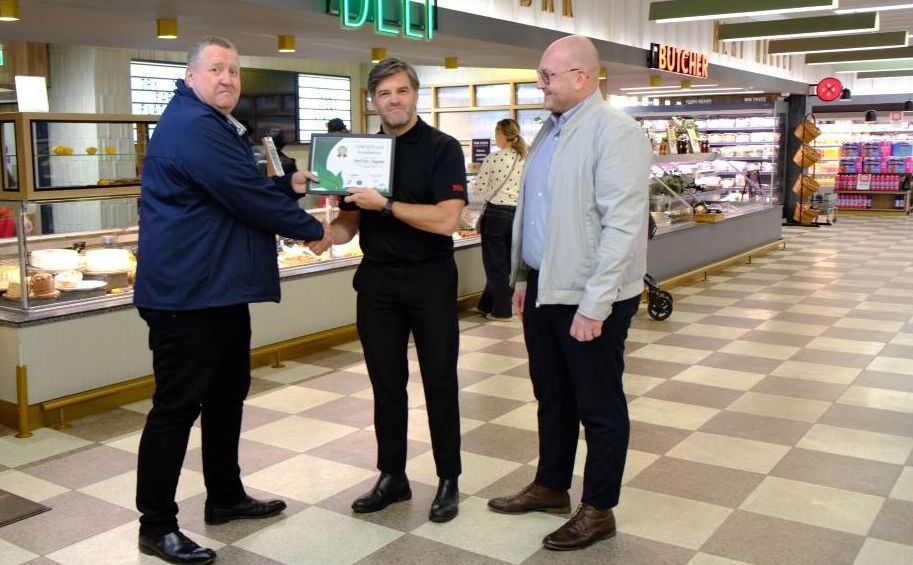 Three people standing together and congratulating a person who received award because of his oustanding food packaging trays from kp