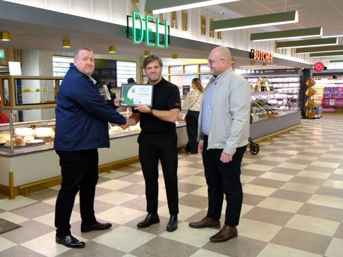 Three people standing together and congratulating a person who received award because of his oustanding food packaging trays from kp
