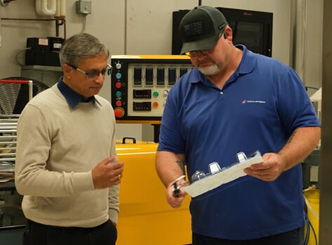 Packaging experts reviewing a thermoformed plastic packaging component in a manufacturing environment, supporting material optimisation, quality assurance and packaging innovation.