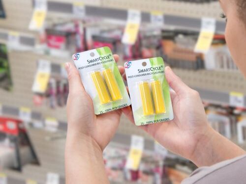 The picture shows a women in the supermarkets with batteries in her hands. The batteries are packaged in kp PVC film