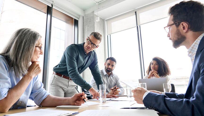 Work colleagues discuss together in a meeting room 