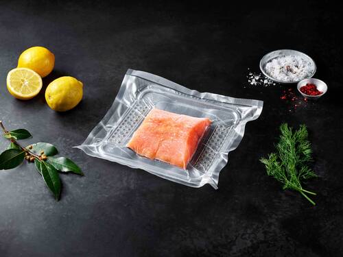 vacuum-sealed salmon in transparent thermoformed plastic packaging with lemon and herbs