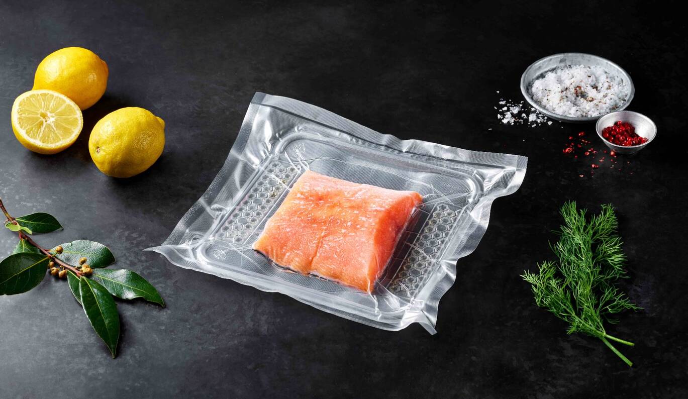 vacuum-sealed salmon in transparent thermoformed plastic packaging with lemon and herbs