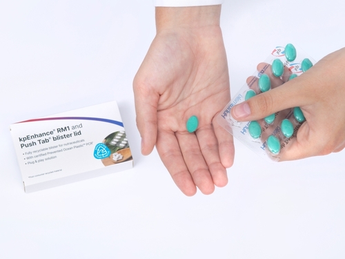 Picture showing transparant blister packaging with green pills on a womans hand